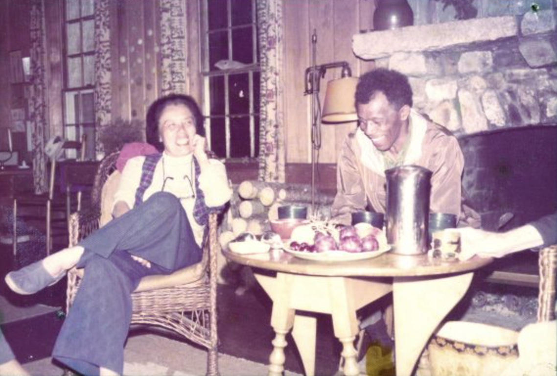 Grace Lee and James Boggs laugh together near a fireplace